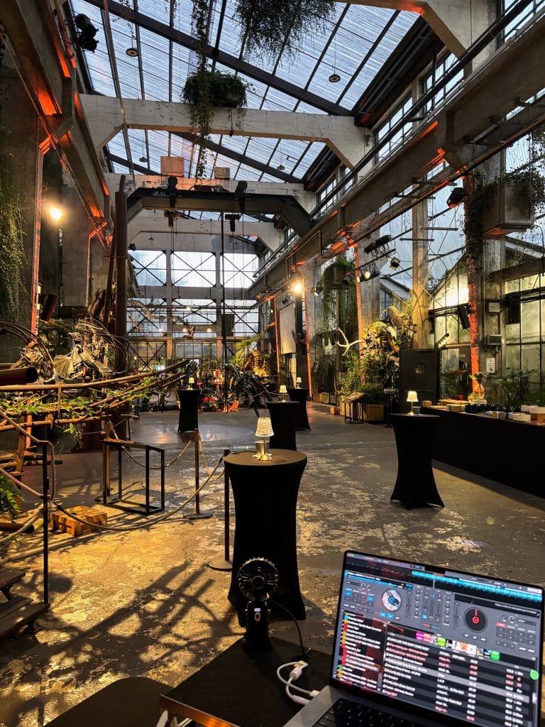 Vue depuis la console du DJ avec logiciel de mixage donnant sur la halle événementielle illuminée.