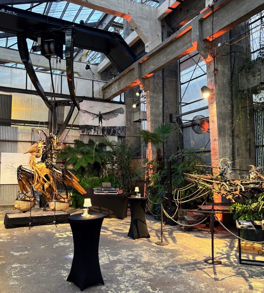 Espace DJ et mange-debout installés au pied des sculptures mécaniques pour un événement d'entreprise à Nantes.