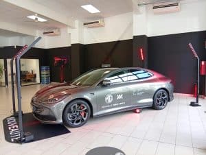 Présentation d'un véhicule MG en concession automobile mis en valeur par un éclairage LED rouge sur mâts autonomes.