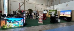 Dispositif vidéo complet avec bandeau LED au sol, totem dynamique et écran géant sur stand de foire expo.