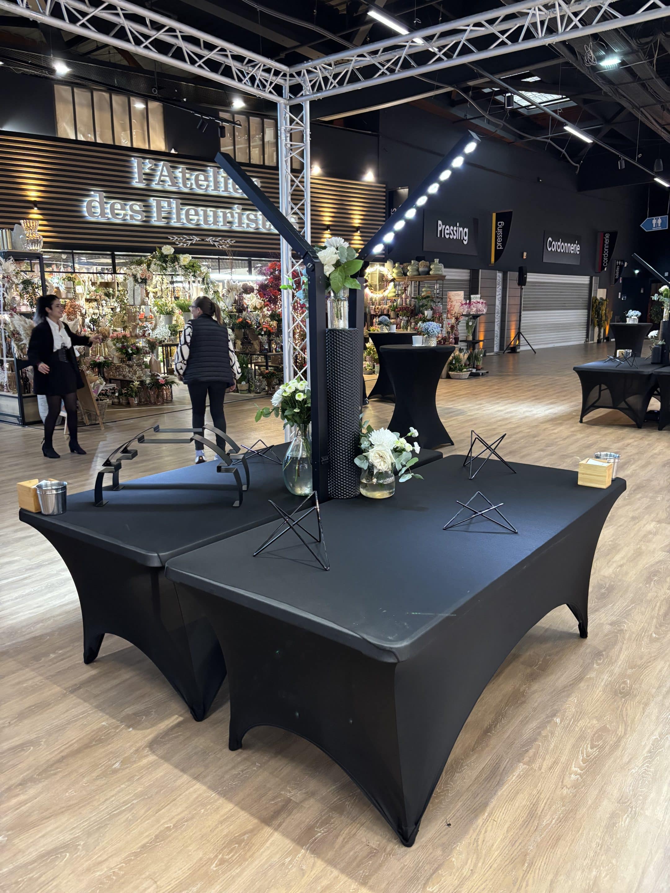 Mât d'éclairage LED autonome illuminant un élégant buffet traiteur avec compositions florales pour une réception.